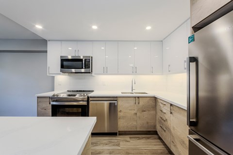 an all white kitchen with stainless steel appliances and white counter tops